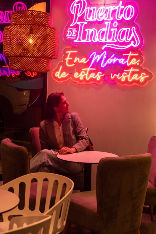 Woman Sitting near Neon at Restaurant