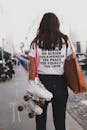 Woman in White Shirt and Denim Jeans Carries Skate Shoes and Tote Bag