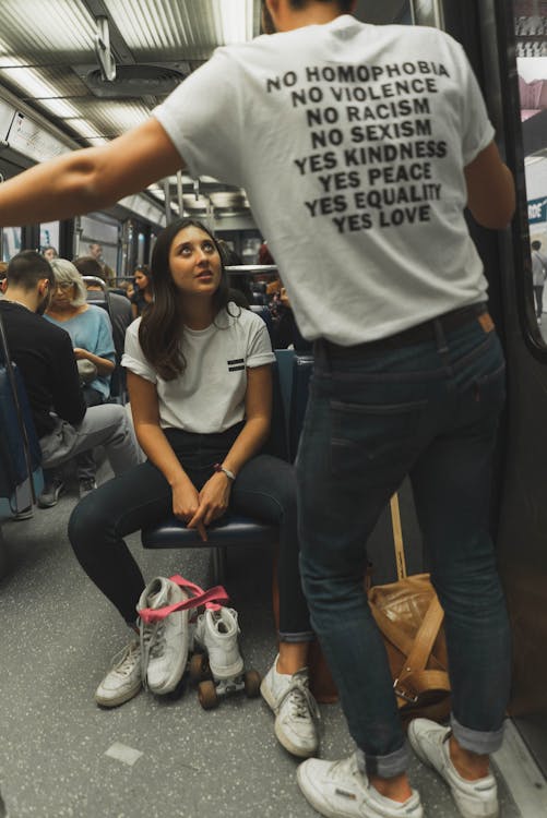 Free Woman Wearing White Crew-neck Shirt and Black Jeans Sitting on Train Seat Stock Photo