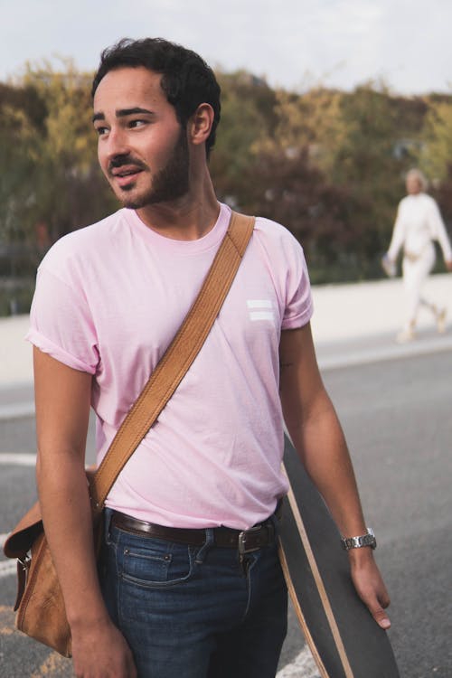 Free A Bearded Man in a Pink Shirt Carrying a Skateboard Stock Photo