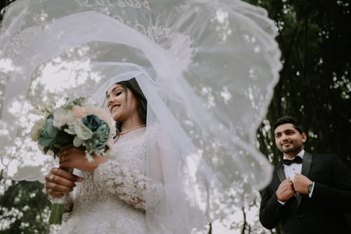 Man in Suit Standing behind Woman in Wedding Dress under Veil