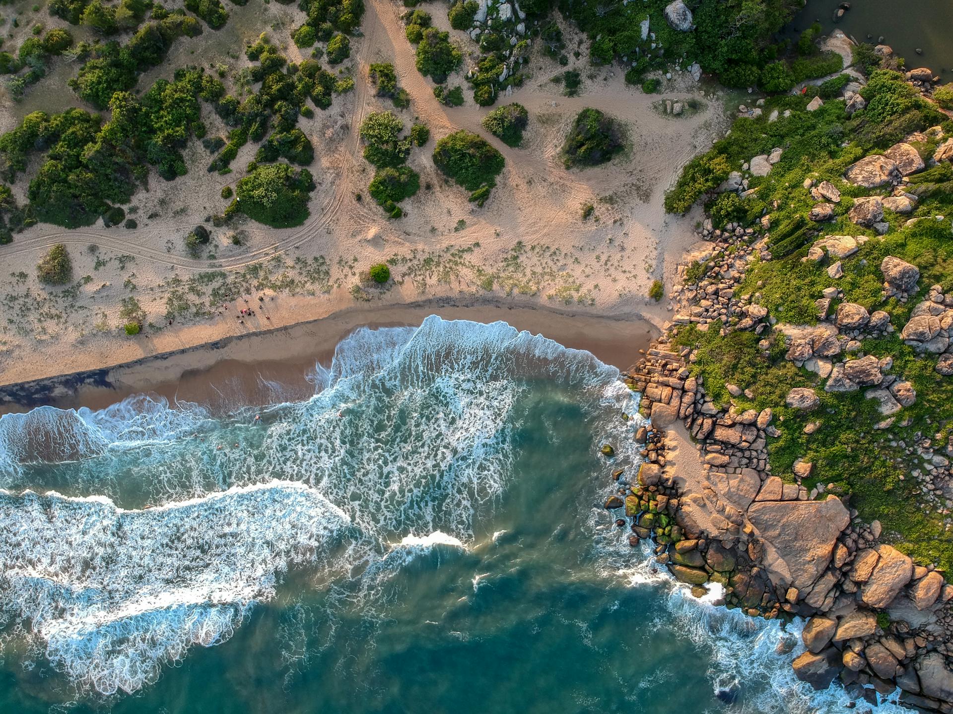 Breathtaking aerial view of lush green coastline in Sri Lanka with rocky cliffs and waves.
