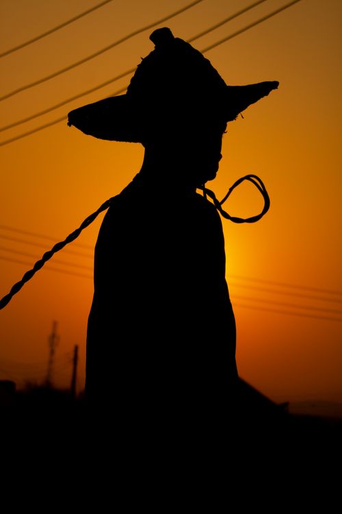 Free A child in silhouette standing at sunset, wearing a wide-brim hat. Perfect for serene and nostalgic themes. Stock Photo