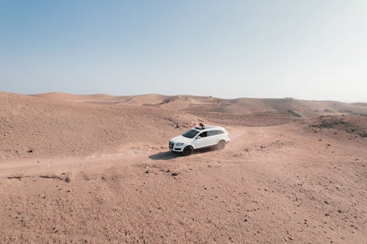 A white SUV off-roading through the sandy desert dunes of Ica, Peru, capturing the thrill of adventure.