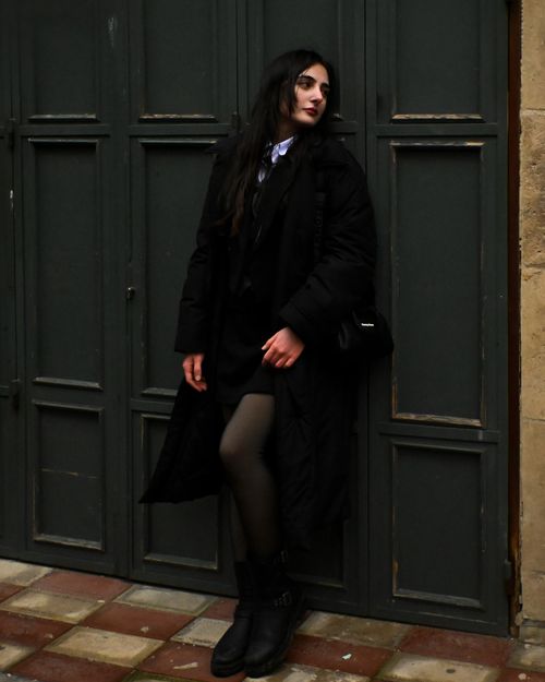 Free Stylish woman posing in a black coat against a green door background. Stock Photo