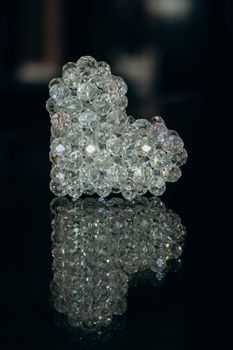 Glittering crystal heart-shaped accessory with intricate reflections on a dark surface.