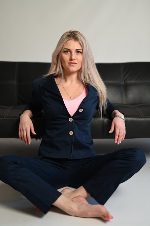 A woman sitting on a black couch with her legs crossed