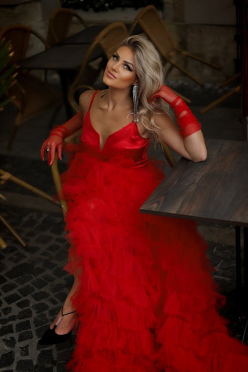 Blonde Woman in Red Dress Sitting by Table