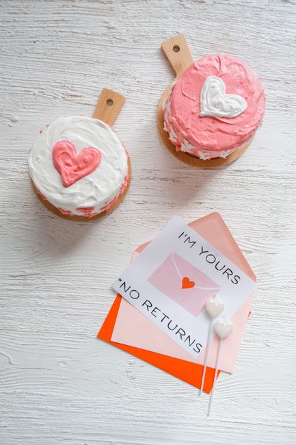 Two heart-decorated cakes with love-themed envelope on white background.