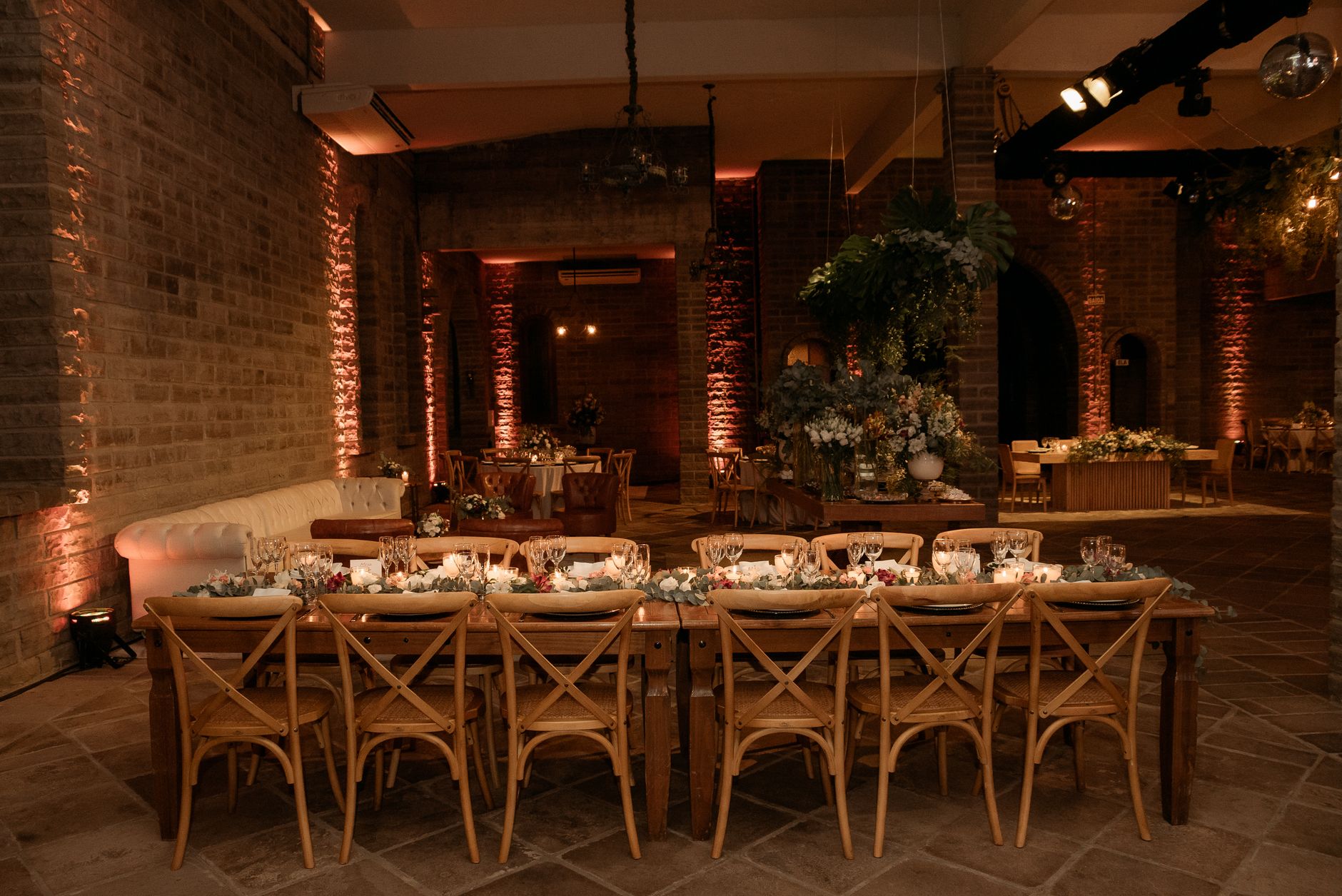 Beautifully decorated indoor event space with wooden tables, chairs, and floral arrangements.