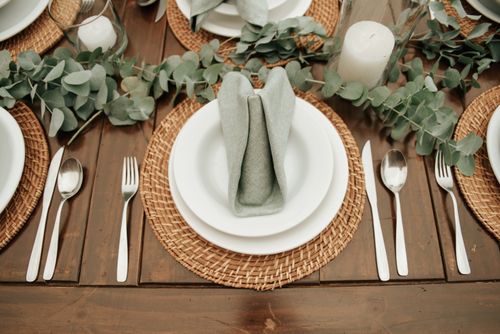 Free A rustic table setting with wicker placemats and elegant silverware featuring candles and greenery. Stock Photo
