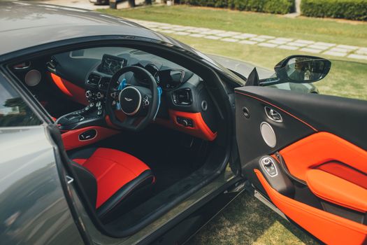 Interior view of a luxury sports car with a sleek design, showcasing open doors and modern features.
