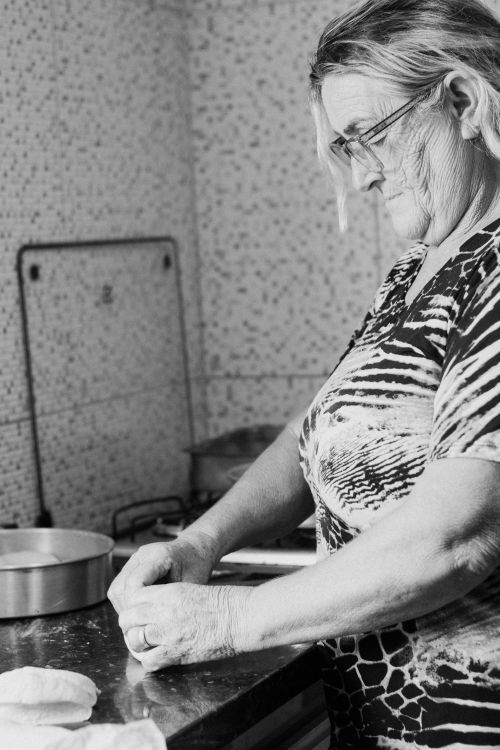 Free Black and white photo of senior woman preparing dough in an indoor kitchen setting. Stock Photo