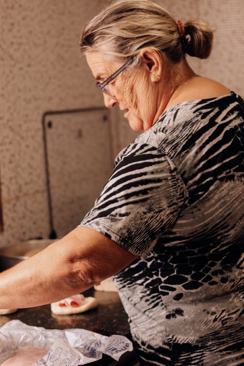 Free Elderly woman wearing eyeglasses baking and preparing food in the kitchen. Stock Photo