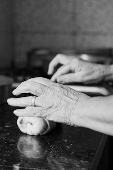 Close-up of elderly hands kneading dough in a kitchen setting, highlighting tradition.