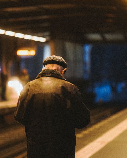 Free Back view of an elderly man in a hat waiting at a Berlin metro station platform. Stock Photo
