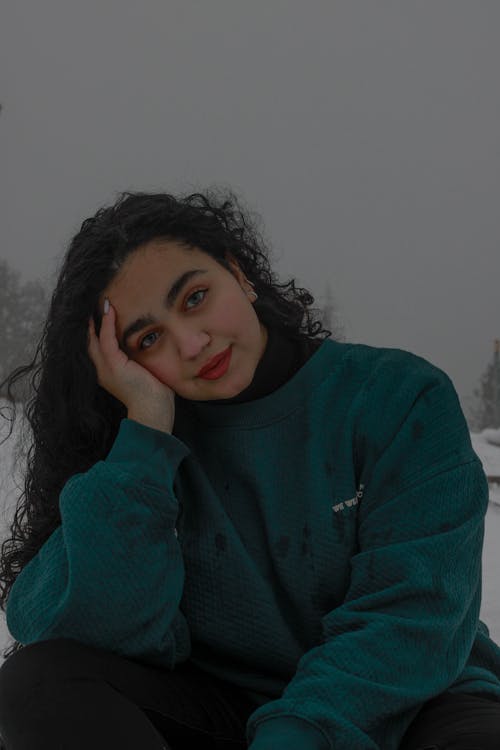 Brunette Woman Sitting with Hand on Cheek