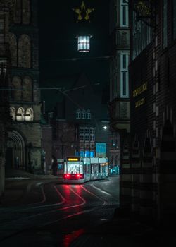 A moody nighttime view of a tram navigating the historic streets of a European city.