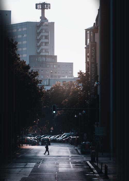 Pedestrian Crosses Urban Street at Dusk