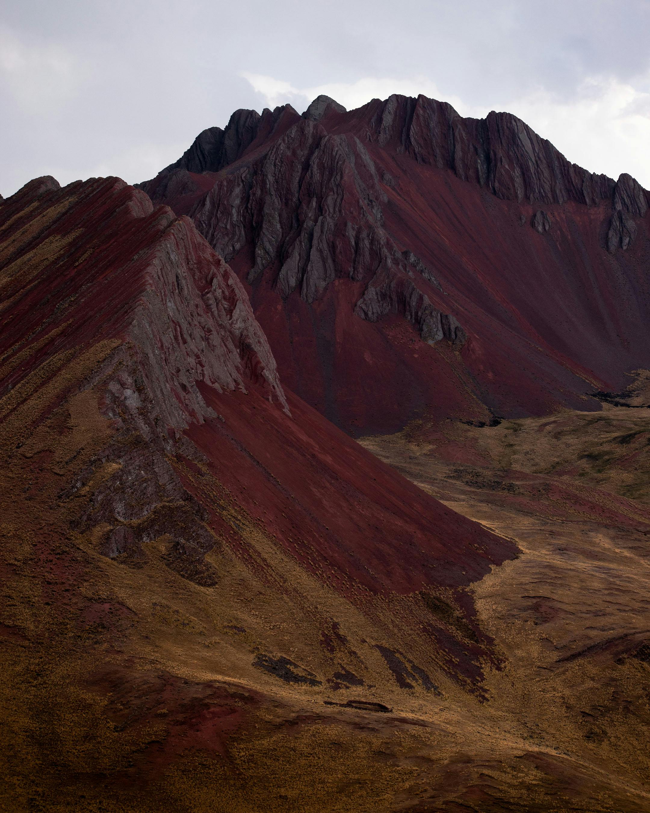 Dramatic view of a red rock canyon and rugged cliffs under a cloudy sky.