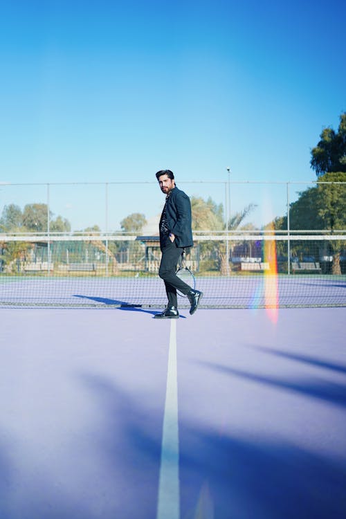 A man in a suit walking on a tennis court