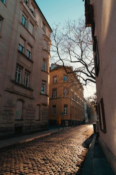 A tranquil city street with cobblestones and sunlit buildings at dusk, creating a serene urban atmosphere.