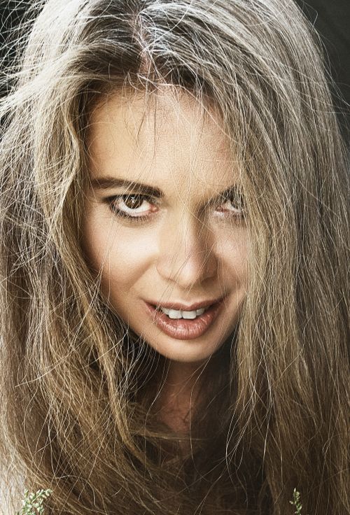 Free Close-up portrait of a woman with long, tousled hair exuding confidence and allure. Stock Photo