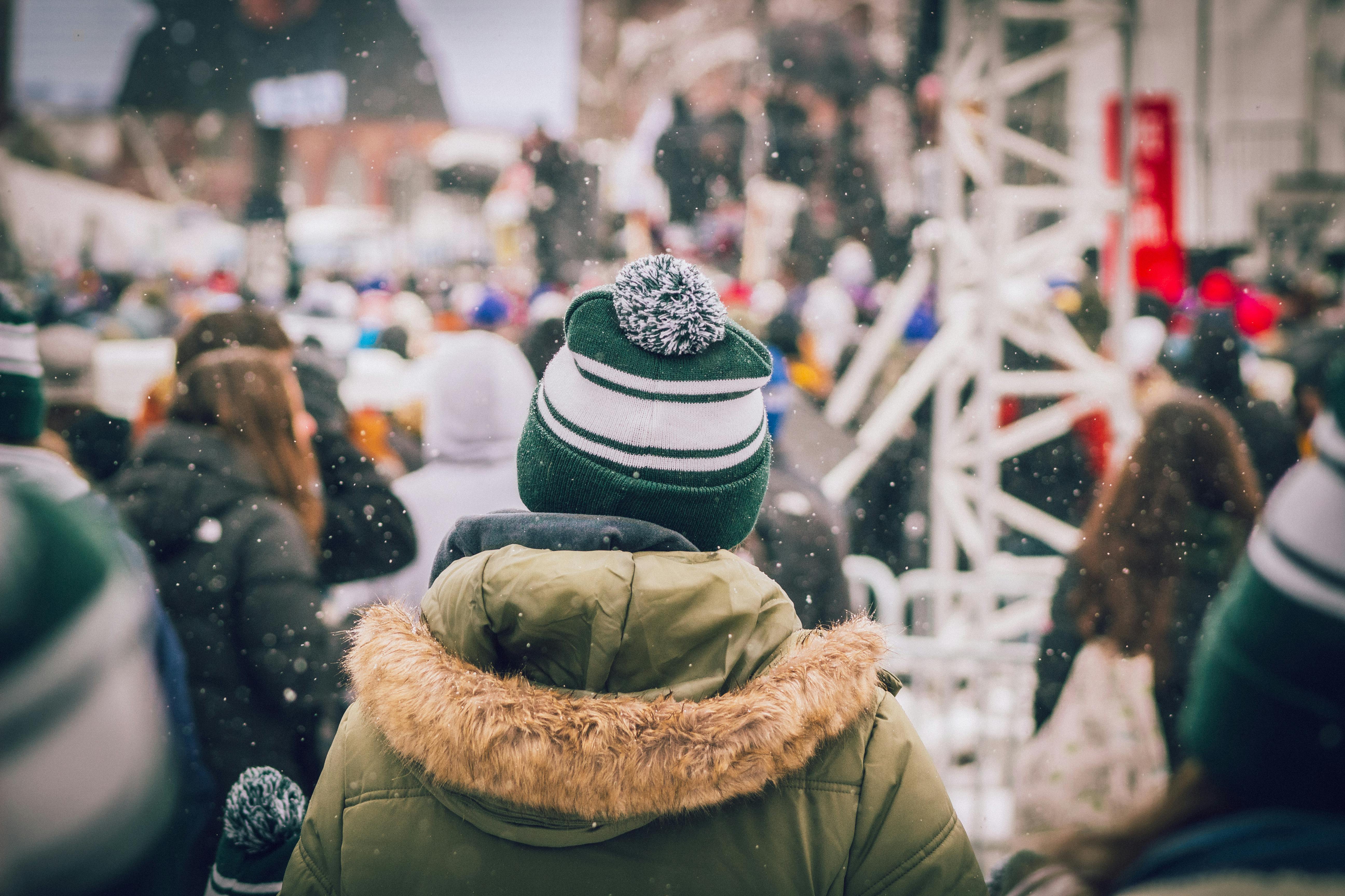 A crowd enjoying a winter outdoor event with snowfall, wearing warm clothing.