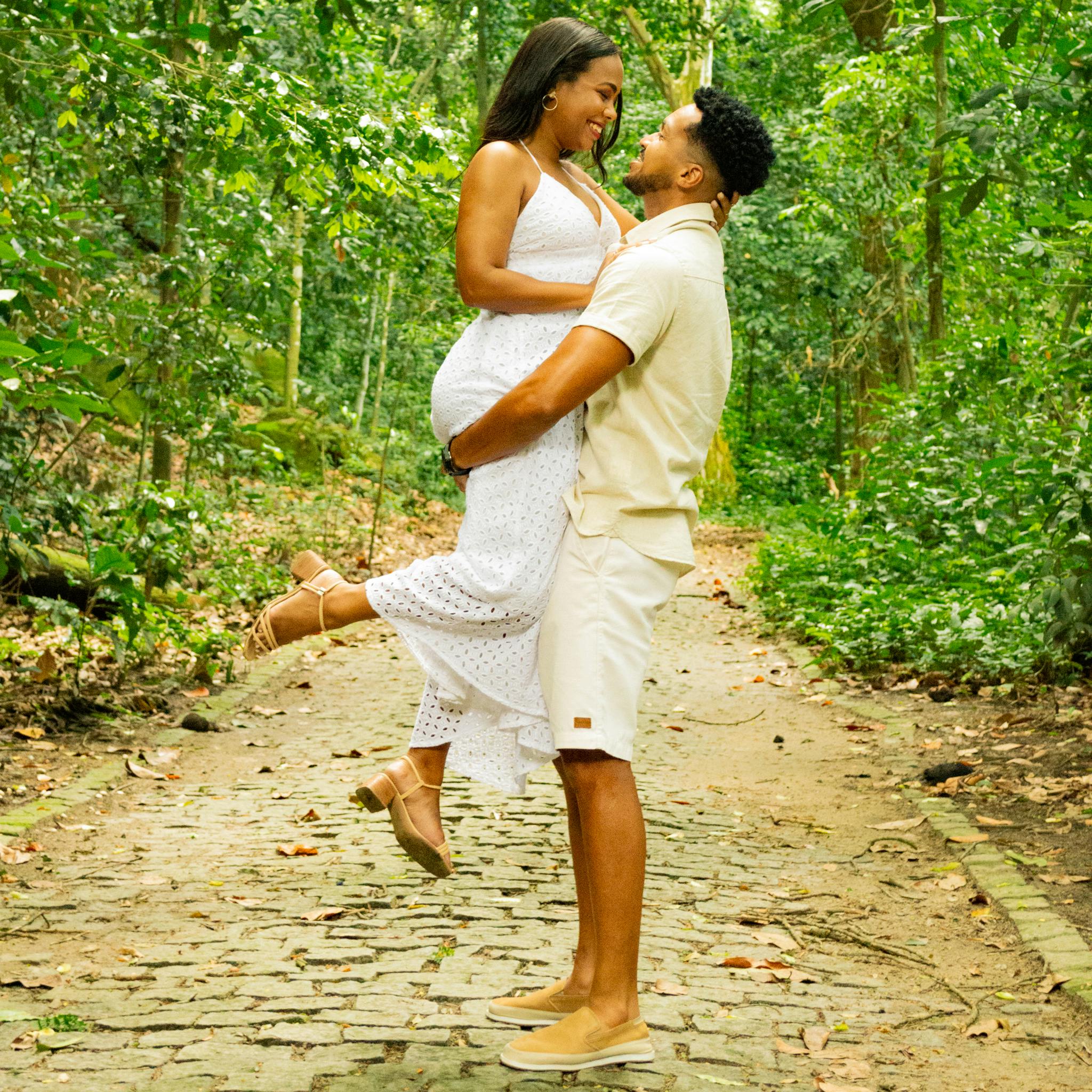 Couple in love enjoying a playful moment on a forest pathway, surrounded by greenery.