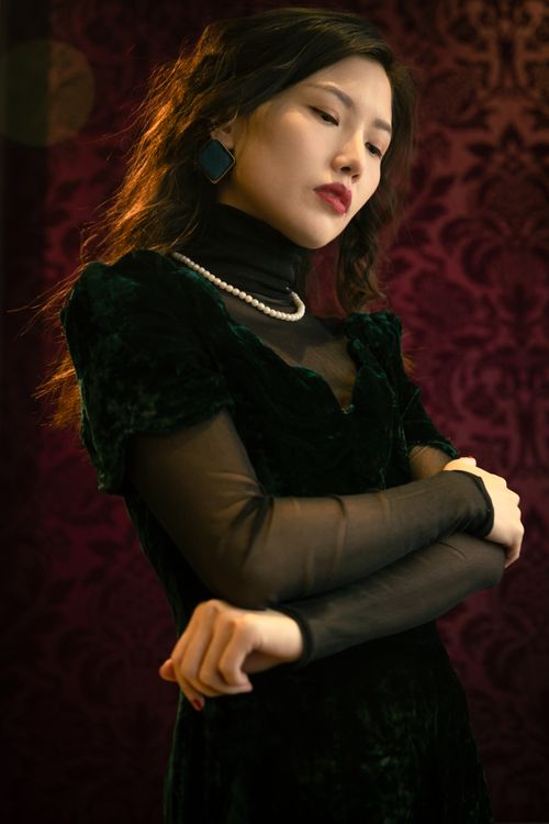 Free Stylish portrait of a woman in a velvet dress and pearls against vintage backdrop. Stock Photo
