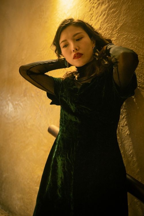 Free Elegant woman wearing a chic velvet dress poses stylishly against a textured wall. Stock Photo