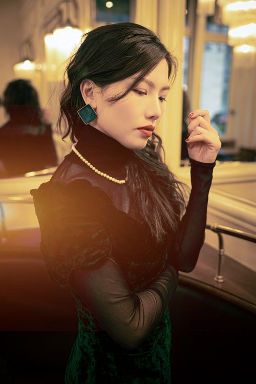Free Portrait of a stylish woman in vintage-inspired attire with pearl necklace indoors. Stock Photo