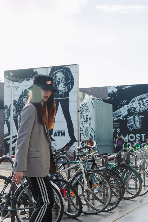 Free A young woman walks past bicycles parked by a mural in the city. Stock Photo