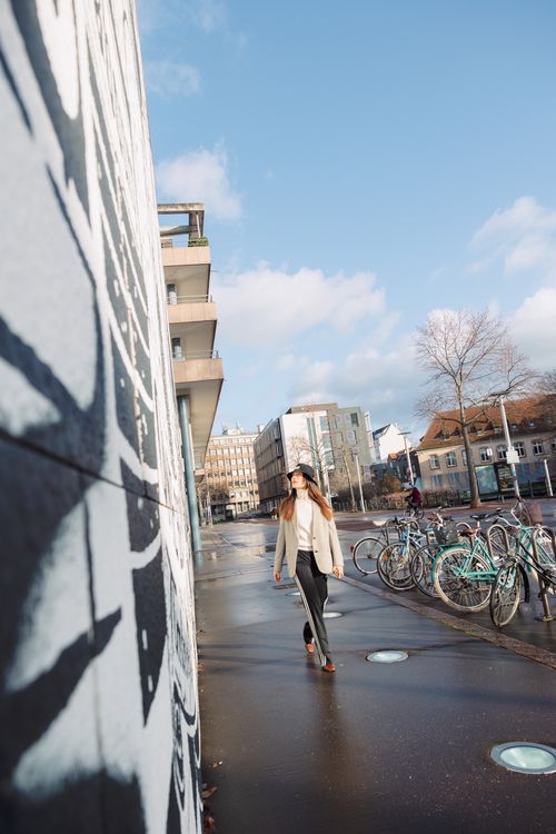 Free A woman in a city street, walking past bikes, buildings, and urban art. Stock Photo