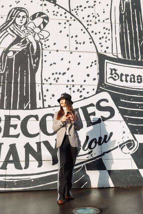 Free Stylish woman standing in front of a striking urban graffiti wall, embodying modern street fashion. Stock Photo