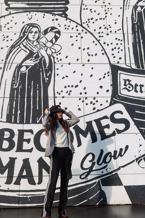 Free Chic woman poses against an urban graffiti mural in city sunlight. Stock Photo