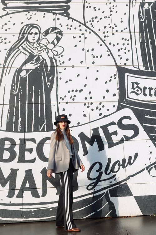 Free Woman poses stylishly in front of monochrome mural wall, showcasing urban art. Stock Photo