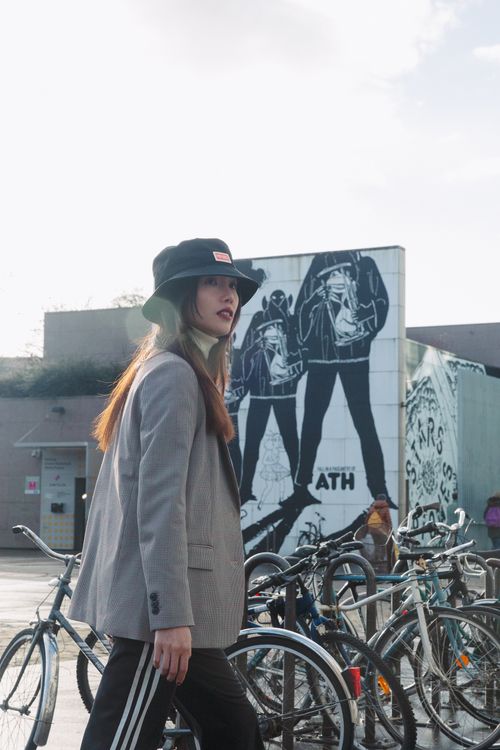 Free Young woman in trendy outfit walking by a city mural with parked bicycles. Stock Photo