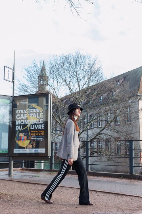 Free Fashionable woman in hat and blazer walking through Strasbourg's urban landscape. Stock Photo