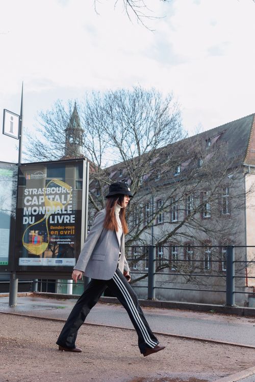 Free Stylish woman walking by a Strasbourg book fair billboard on a city street. Stock Photo