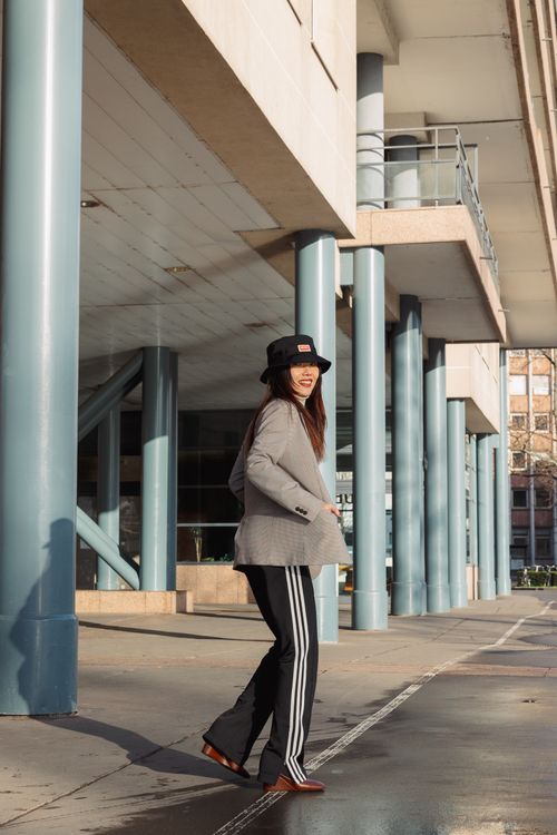 Free A stylish young woman smiles while walking outdoors near a modern building. Stock Photo