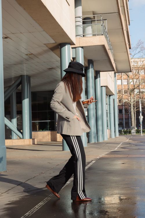 Free Stylish woman in hat walking on a city sidewalk, captured in natural sunlight. Stock Photo