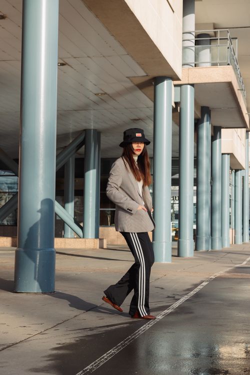Free Woman in stylish attire walking through urban setting under striking modern architecture. Stock Photo