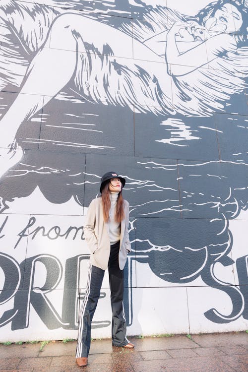 Young Fashionable Woman Standing near a Wall with a Mural 