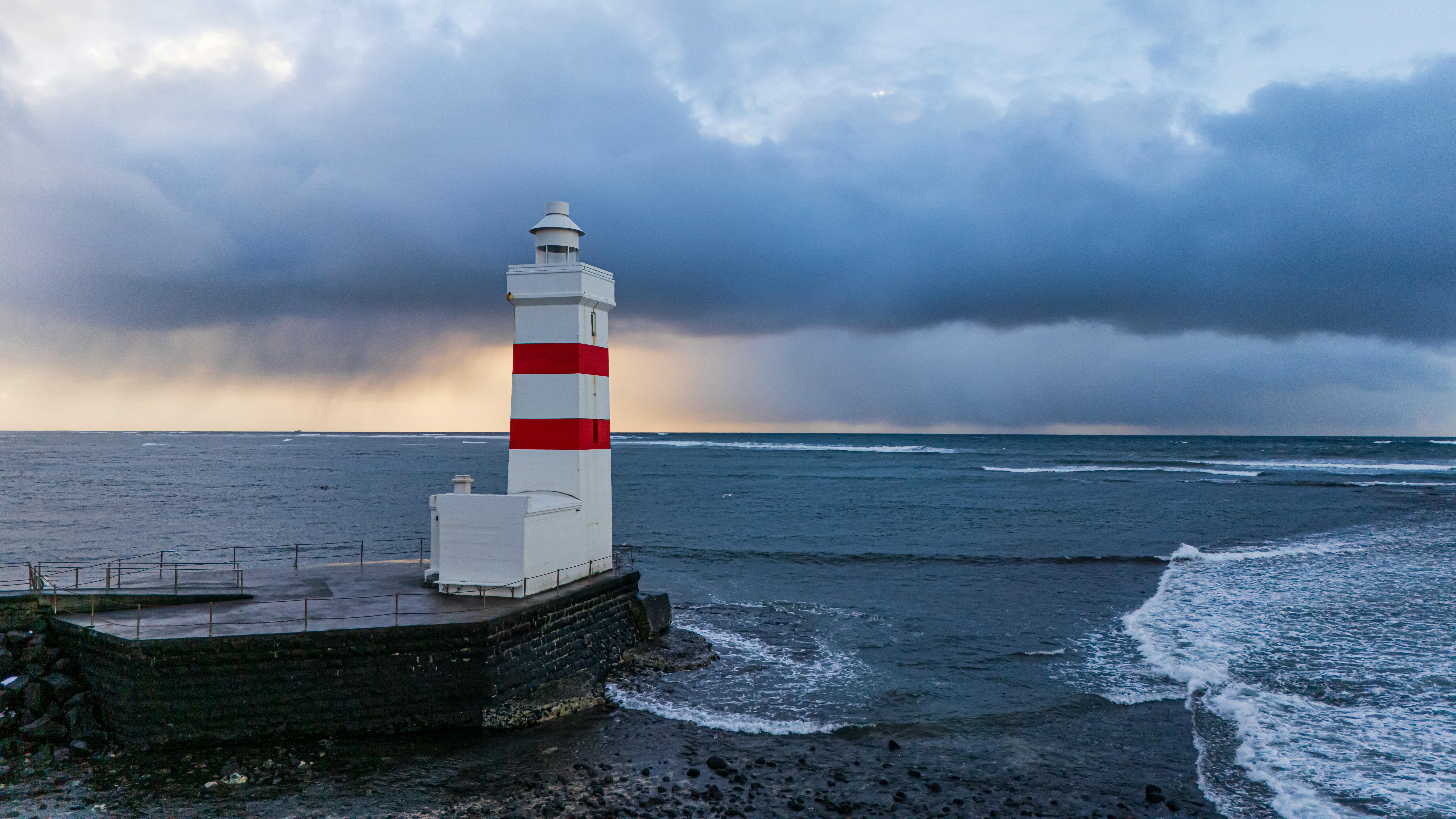 A stunning view of the Garðskagaviti Lighthouse against the dramatic ocean backdrop in Iceland.