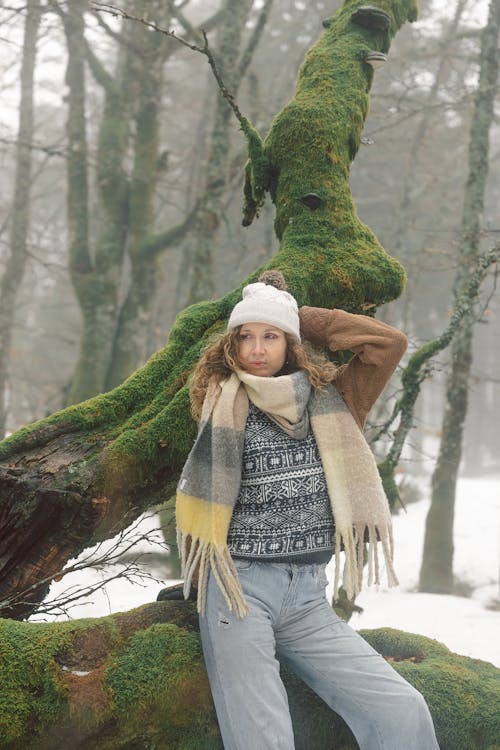 Female Model Leaning on a Moss-Covered Tree in a Winter Forest