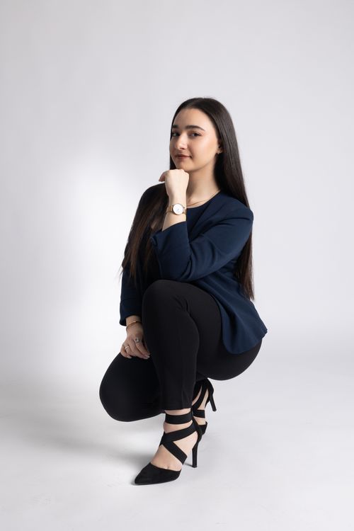 Free Young woman in a stylish pose with black attire and heels on a white background. Stock Photo