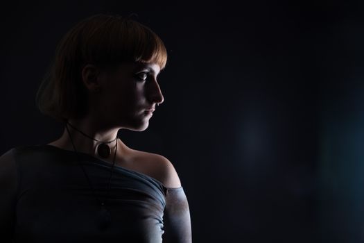 Dramatic side profile portrait of a woman in dim lighting, creating a mysterious atmosphere.