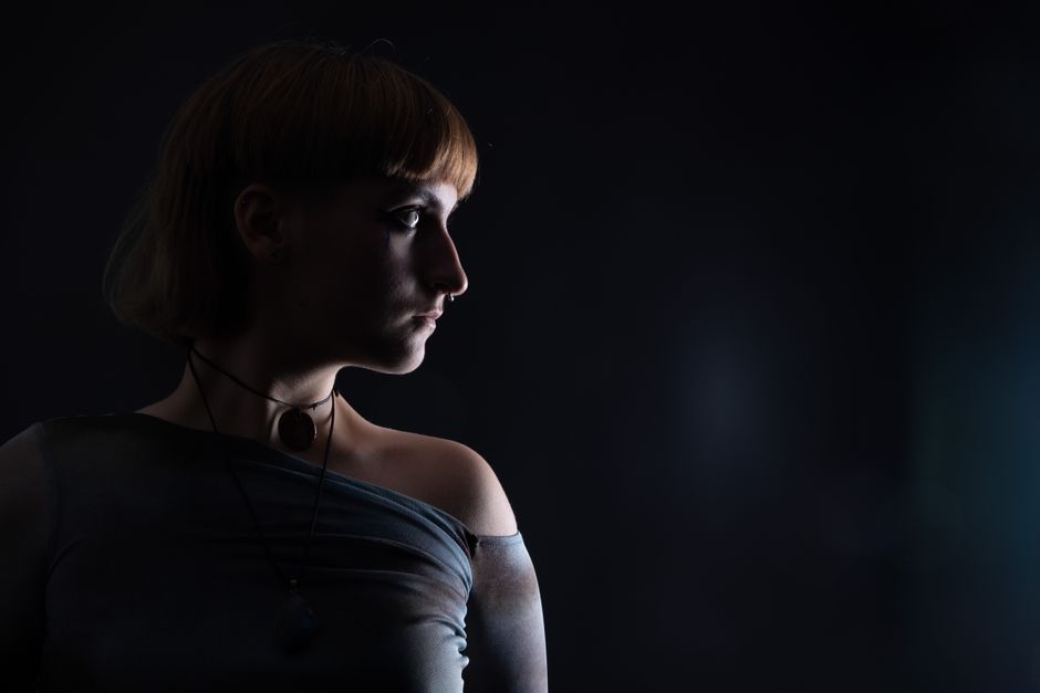 Dramatic side profile portrait of a woman in dim lighting, creating a mysterious atmosphere.