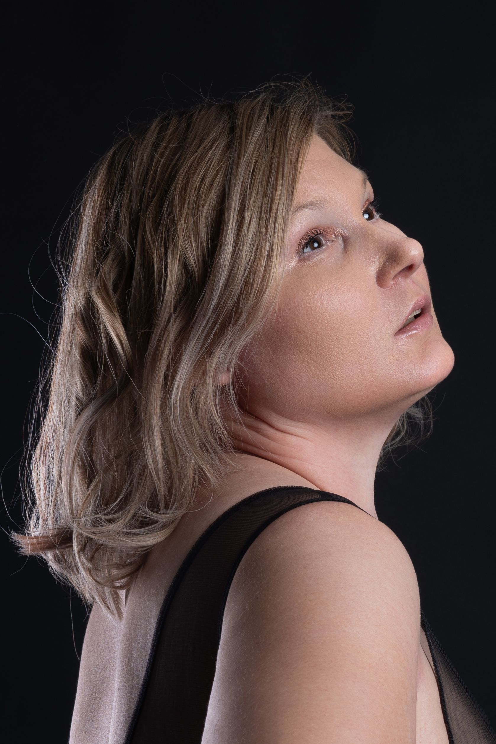 Stylish portrait of a blonde woman against a dark background, showcasing elegance and fashion.